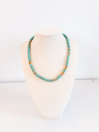 Necklace with turquoise and orange beads on a mannequin against a white background
