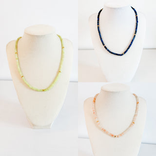 Three necklaces on mannequin heads against a white background
