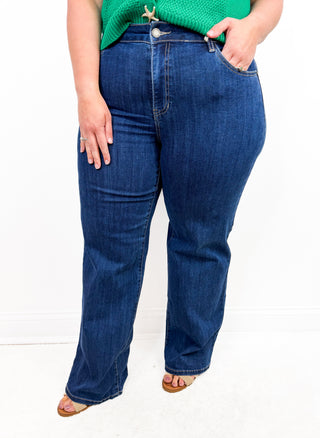 Person wearing blue jeans and a green top on a white background